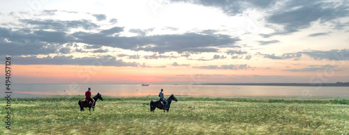 two people riding two horses in the field in the wild nature