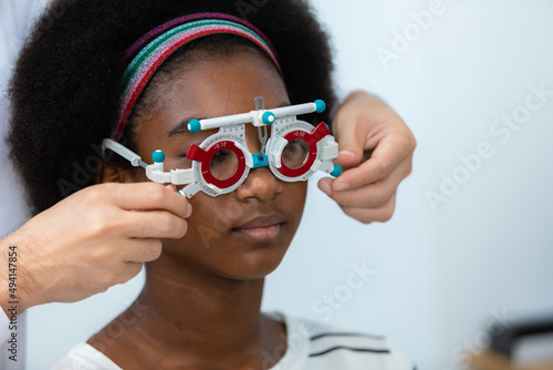 young woman african american wear trial frame eye test ophthalmological in optics clinic. woman checkup eye health with equipment opthalmology medical in hospital.