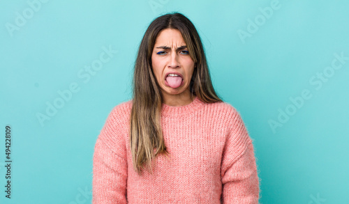 pretty hispanic woman feeling disgusted and irritated, sticking tongue out, disliking something nasty and yucky