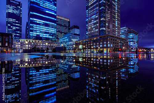 Night city view of business buildings around the Marunouchi side of Tokyo Station after rain. Reflection photo with beautiful specular reflection.