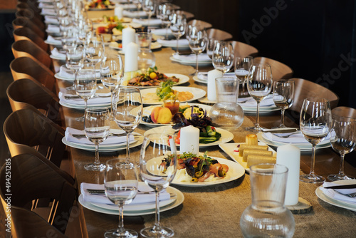 Glasses, forks, knives, plates on a wooden table in restaurant served for holiday. Festive table setting in restaurant.