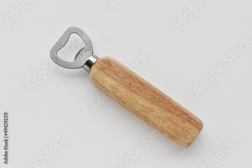 A top view image of a wooden handled bottle opener on a light grey background. 