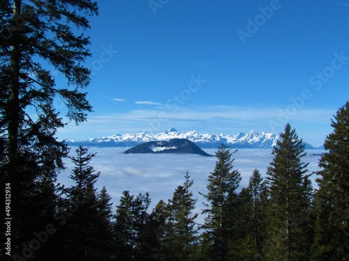 View of Triglav mountain and Julian alps with the peaks covered in snow in Gorenjska region of Slovenia covered in stratus clouds or fog