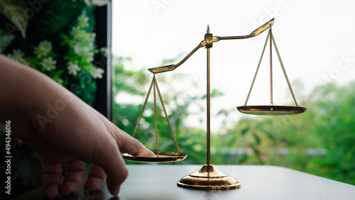 Tip the scales of justice concept as a the hand of a person illegally influencing the legal system for an unfair advantage.