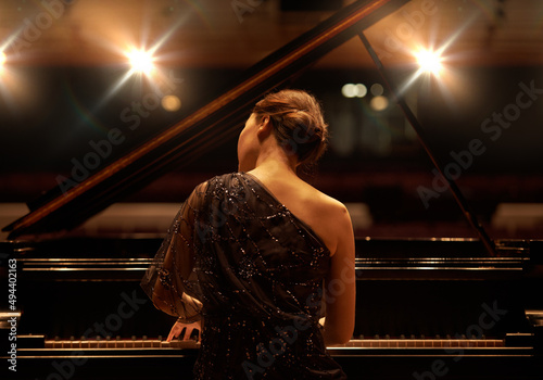 Performing for the audience. Shot of a young woman playing the piano during a musical concert.