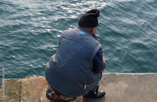 Alter Mann sitzt am Kai, Fischen ohne Angel in Qingdao