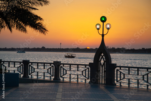 Enchanting sunset in Abu Dhabi Corniche with silhouetted traditional boat passing by