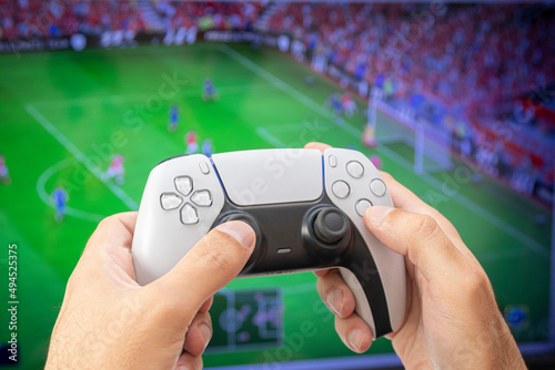 Man holding game controller playing football game.