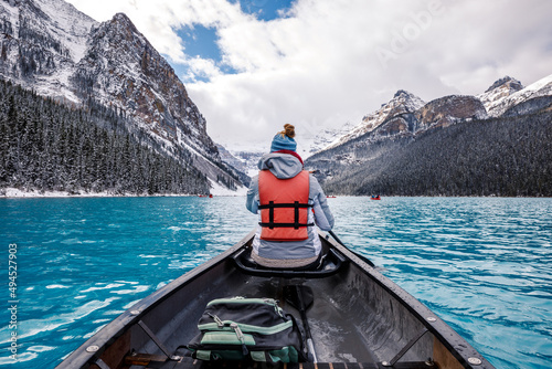 Back view of a hiker in a lifejacket in a sailboat on lake Louise in Canada