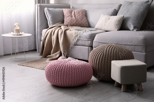 Stylish poufs and ottoman near sofa in living room. Interior element