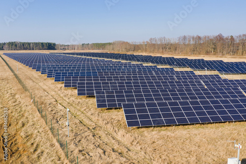 Farma paneli solarnych na równinie pokrytej suchą żółtą trawą.