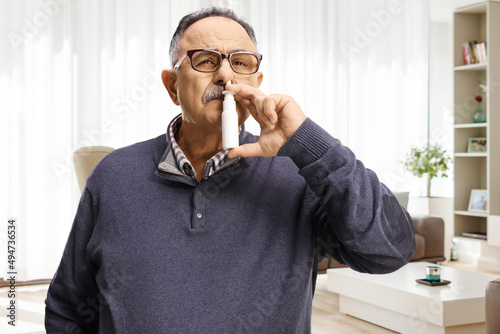 Mature man using a nasal spray at home