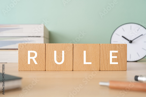 「RULE」と書かれた積み木、ペン、ノート、本、置き時計