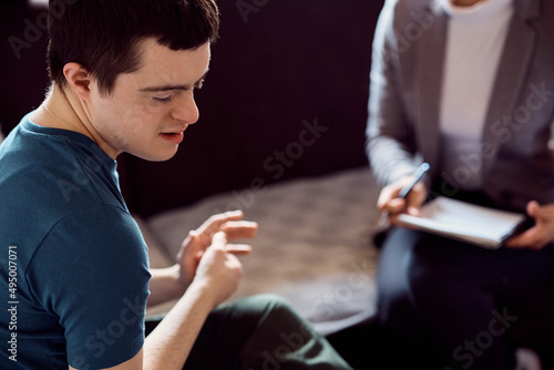 Shy down syndrome man during conversation with psychologist at home.