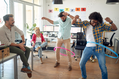 A group of employees is having fun while playing with hula-hoop in the office. Employees, job, office
