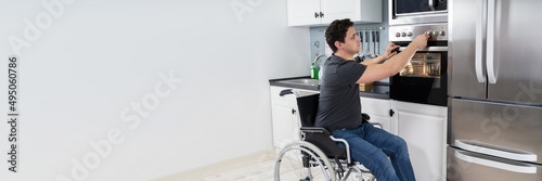 Disabled Man Using Microwave Oven In Kitchen