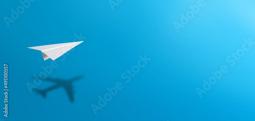 White paper plane casting shadow of airplane on blue background. Concept for travel, business idea, leadership, success, teamwork, creative idea, vision.