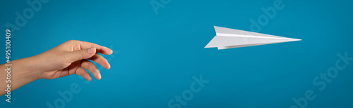 Hand throwing paper plane isolated on blue background. concept new innovation and creativity.