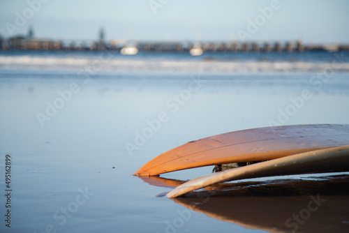 Two surfboards on the beach at sunset with jetty in the distance. Coffs Harbour, NSW Australia