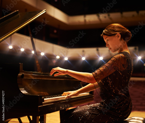 Hitting the right notes. Shot of a young woman playing the piano during a musical concert.