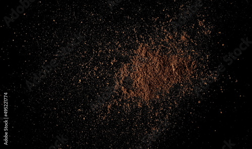 Ground, milled nutmeg powder isolated on black, top view