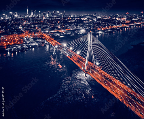 Beautiful panoramic aerial drone skyline view of the center of night Warsaw with skyscrapers in the background with the Swietokrzyski suspension bridge - the lights of the big city by night, Poland