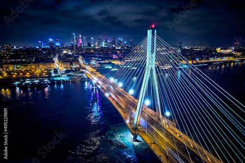 Beautiful panoramic aerial drone skyline view of the center of night Warsaw with skyscrapers in the background with the Swietokrzyski suspension bridge - the lights of the big city by night, Poland