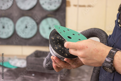 A person changes green sandpaper for a sander. The master changes the emery wheel on the grinder. An abrasive disc for an orbital grinder.