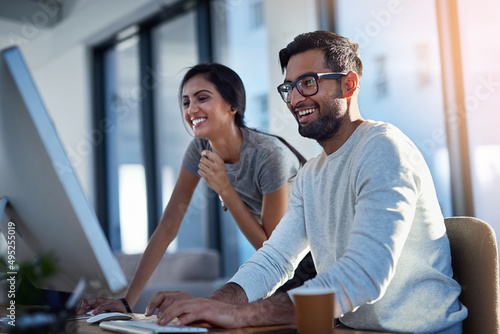 Share what makes you happy. Shot of two young coworkers using a computer together at work.