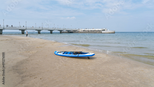 Beach of the Baltic Sea near Kolobrzeg in Poland with stand up paddle board and pier in the background