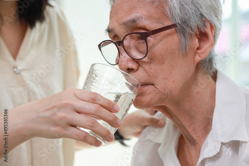 Nurse or caregiver gives drinking fresh water to senior woman in hospital or nursing home,Thirsty elderly grandmother suffering from heat,exhausted and dehydrated,health care,healthy lifestyle concept