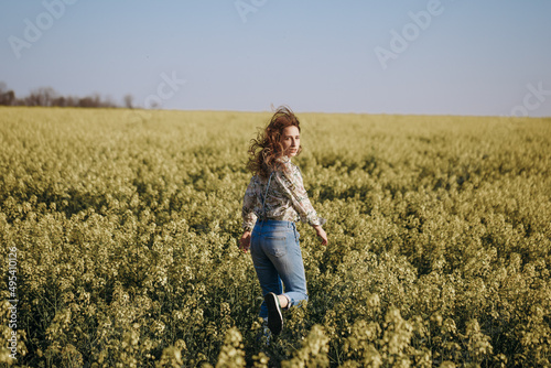 Woman run away through the flowering field and looking back