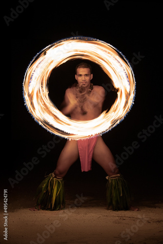 Polynesian male Fire dancer performing with spinning flame
