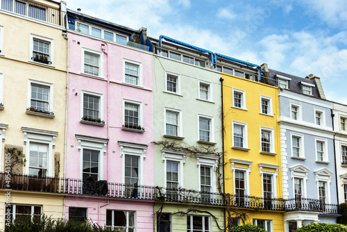Colourful terraced townhouses with summer sky background. The area of Notting Hill, London, is famous for streets of houses with brightly painted exteriors.