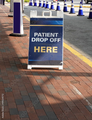 Sandwich board sign on a brick sidewalk near a driveway that says, Patient Drop Off Here