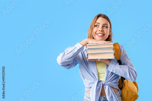 Female student with books on blue background