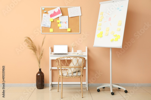 Modern workplace with sticky notes and flipchart near beige wall