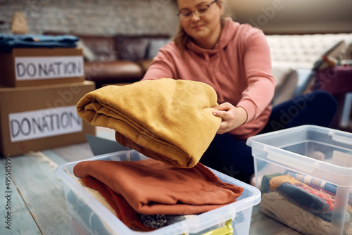 Close-up of woman sorting clothes while packing donation boxes for charity.