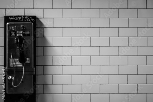 Black and white shot of a payphone a brick wall background