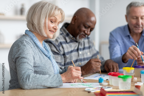Good-looking senior lady enjoying painting activity with her friends