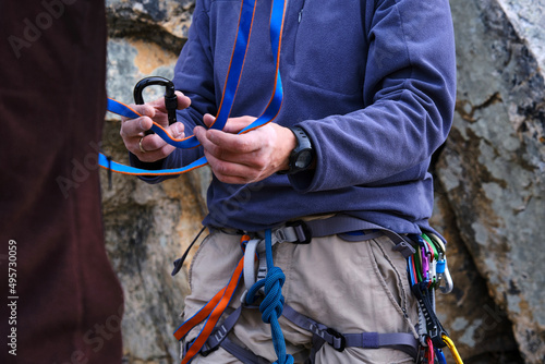 Rock climbing instructor is teaching how to perform the belay station. Unrecognizable peoples