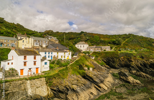 The houses of Portloe on top of the cliffs overlooking the harbour and cove at low tide. Portloe is a traditional Cornish fishing village on the Roseland Coast.