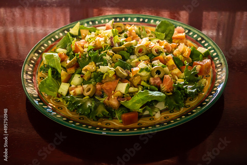 Um prato de salada sobre superfície reflexiva.