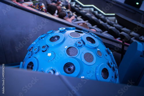 Closeup of a planetarium projector with people enjoying the experience in the background