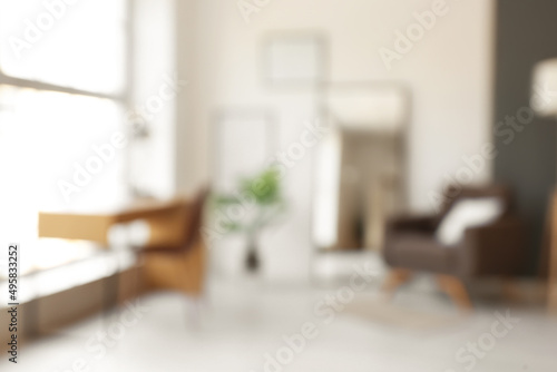 Interior of stylish room with armchair, workplace and mirror, blurred view