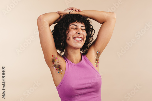 Unshaven young woman flaunting her confetti-decorated arm pits