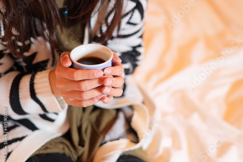 ベッドの上でコーヒーカップを持つ女性