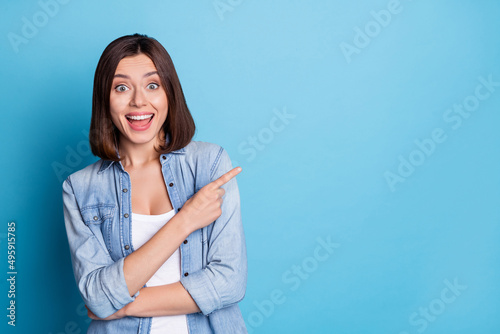 Photo of excited astonished person direct finger empty space offer proposition isolated on blue color background