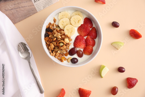 bowl of granola cereal with yogurt and berries isolated on eggnog color background