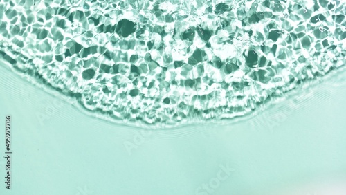 Single wave from above making ripples and splashes on water surface on mint green background | Cosmetic product background